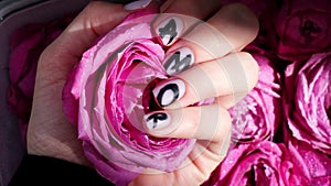 AMOR word on nails manicure hold Pink rose flower on black silk fabric. Minimal flat lay nature. Female hand. Love