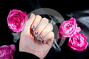 AMOR word on nails manicure hold Pink rose flower on black silk fabric. Minimal flat lay nature. Female hand. Love