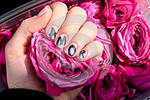 AMOR word on nails manicure hold Pink rose flower. Minimal flat lay nature. Female hand. Love