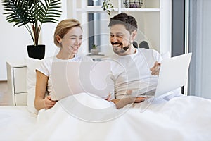 Amorous people spending time together using laptop in bed