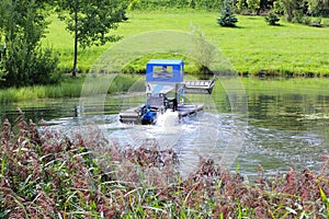 Amphibious machine mowing algae on still water photo