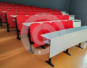 Amphitheater red chairs and white tables for students lined in rows for university or conference lectures photo