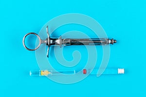 Ampoule with anesthesia, lidocaine or novocaine, needle and vintage metal syringe  on blue background, dental health and photo
