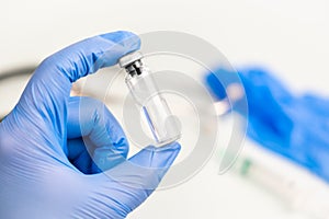 Ampoule for internal injection in the hands of a doctor in medical gloves, with syringe, blurred background of a medical worker.