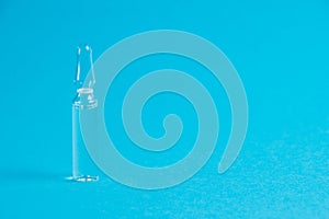Ampoule with medicine on a blue background close-up macro, copy space. Treatment concept for coronavirus patients