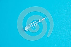 Ampoule with medicine on a blue background close-up macro, copy space. Treatment concept for coronavirus patients