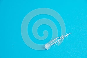 Ampoule with medicine on a blue background close-up macro, copy space. Treatment concept for coronavirus patients