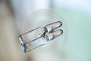 Ampoule with medicine lies on a mirror close-up photo