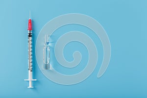 Ampoule with medicine and syringe on a blue background, top view. photo