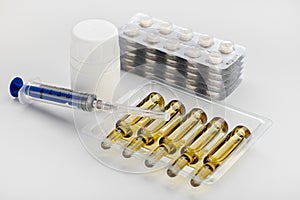 Ampoules with medicine, pills in  blister and  disposable syringe on  white background.