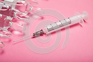 Ampoules and syringe for injection on a pink background, concept photo