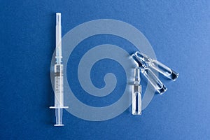 Ampoules with a vaccine and a syringe on a blue background.