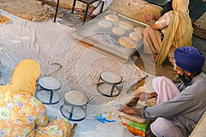 Amritsar, India - November 21, 2011: Unknown Indian people cook national bread for a free meal for pilgrims. Golden Temple in