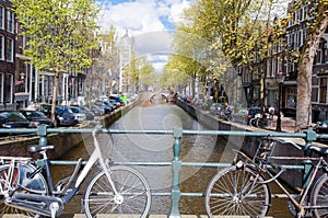 Amsterdam canal with bikes on the bridge and parked cars along the bank. Netherlands.