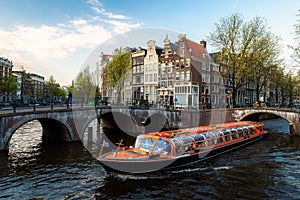 Amsterdam canal cruise ship with Netherlands traditional house in Amsterdam, Netherlands