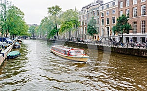 Amsterdam canal cruise ship with Netherlands traditional house.