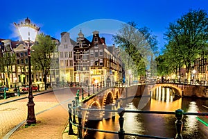 Amsterdam canal with typical dutch houses and bridge during twilight blue hour in Holland, Netherlands