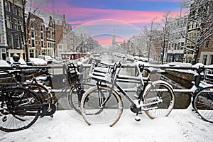 Amsterdam covered with snow with the Westerkerk in winter in the Netherlands at sunset