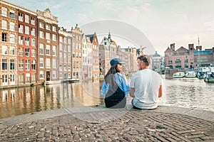 Amsterdam Damrak during sunset, happy couple man and woman on a summer evening at the canals