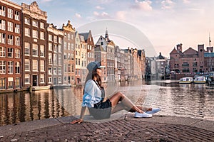 Amsterdam Damrak during sunset, happy woman on a summer evening at the canals