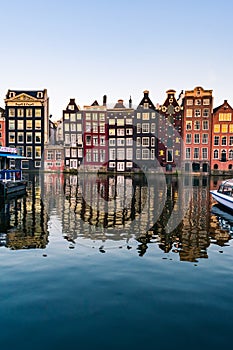 Amsterdam houses with colorful facades and cruising boats at the Amstel river canal