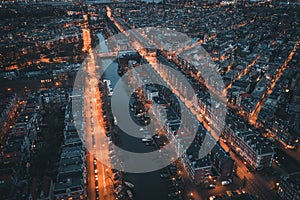 Amsterdam, Netherlands. Aerial top view of old city from above at night with canals and houses