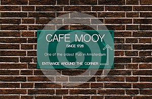 Green plate on a red bricked wall informing that the pub called Cafe Mooy was established in 1726