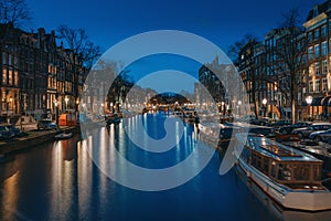 Amsterdam night city skyline at water canal waterfront with boat houses, Amsterdam, Netherlands