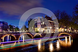 Amsterdam by night with floating boats on the river canal , evening time , travelling to Netherlands