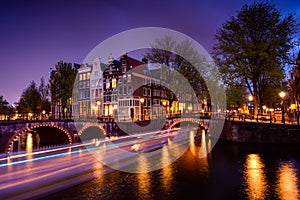 Amsterdam by night with floating boats on the river canal , evening time , travelling to Netherlands