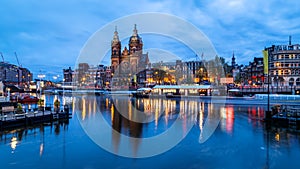 Amsterdam, night view of Basilica of Saint Nicholas and old town skyline reflected in canal.