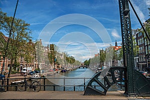 Bicycle at bascule bridge on canal with old buildings and blue sky in Amsterdam.