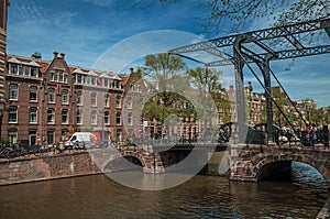 Canal with brick buildings, bascule bridge, bicycles and blue sky in Amsterdam.