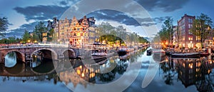 Amsterdam. Panoramic view of the historic city center of Amsterdam. Traditional houses and bridges of Amsterdam. A blue evening