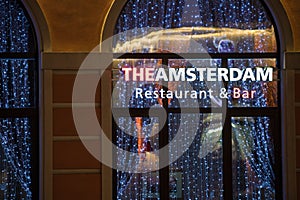 The Amsterdam Restaurant and Bar exterior in Rosa Khutor ski resort with neon sign and festive interior seen through transparent w