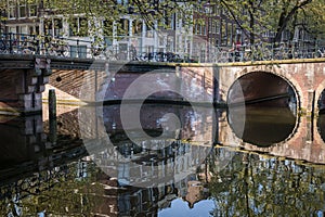 Amsterdam`s bridges reflect in the waters of one of its canals