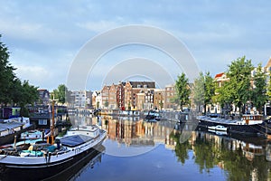 Amsterdam scenery with house-boat and ancient gabled houses at daybreak, Netherlands