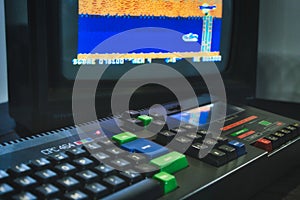 Amstrad CPC 464 keyboard and monitor displaying a retro computer game