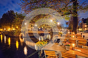 Amterdam cafe tables, canal, bridge and medieval houses in the e