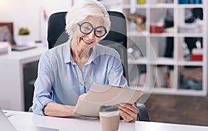 Amused aged woman working in the office