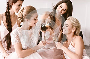 Amused bride and bridesmaids having hen party at home photo