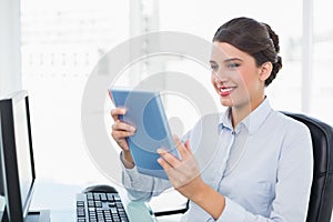 Amused classy brown haired businesswoman using a tablet pc