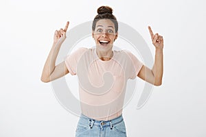 Amused delighted and optimstic good-looking caucasian girl with tan and hairbun raising index finger to point up smiling