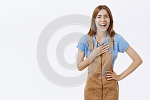 Amused and entertained charming enthusiastic woman in brown overalls bending holding hands on waist holding palm pressed photo