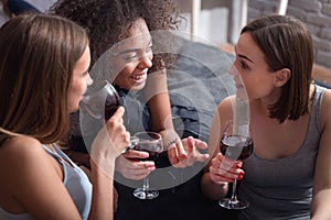 Amused girls drinking wine and having exciting conversation