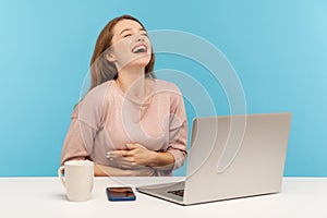 Amused happy woman employee laughing out loud, holding her stomach and being hysterical at crazy joke