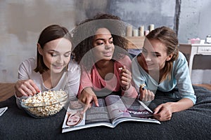 Amused involved girls reading the magazine at home