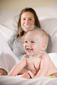Amused six month old baby with mom in background photo