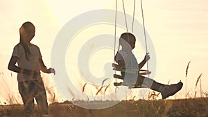 Amusement park dream concept. Happy girl swinging on a swing in the park at sunset. child plays with wooden swing