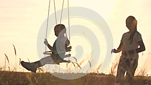 Amusement park dream concept. Happy girl swinging on a swing in the park at sunset. child plays with wooden swing